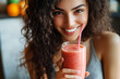 © Виктория Марьенко - Happy young woman drinking a fresh fruit smoothie with a straw in her cozy kitchen