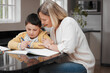 © peopleimages.com - Mother, student or helping with homework in home for learning support, art assignment or creative encouragement. Education, woman or boy with books for drawing, study and homeschool lesson in kitchen