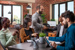 © DC Studio - African American manager shakes hands with caucasain male employee during team meeting in modern office. Colleagues sitting at table with materials for company discussion as two men greet each other.