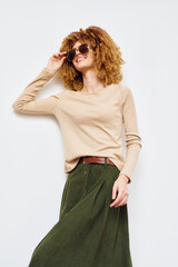 Canvas Print - female model in casual outfit, sunglasses, long sleeve top, and skirt, posing against a light background, focusing on fashion and style trends for modern women