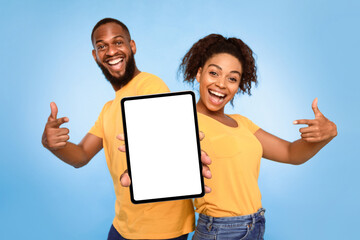 Wall Mural - joyful african american couple pointing at tablet screen with mockup for design, advertising new app