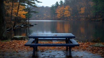 Wall Mural - A blue picnic table sits by a lake in autumn