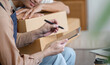 © wichayada - LGBT couple focused on online sales, taking notes and brainstorming ideas together at home