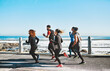 © peopleimages.com - Sports, health and people running by beach for race, marathon or workout training together. Fitness, activity and group of athletes with cardio exercise for wellness outdoor by ocean in morning.