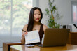 © Crystal - Asian businesswoman having video conference and showing financial report at home office