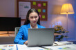 © Crystal - Young Asian businesswoman working late using laptop in office at night