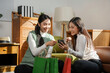 © Crystal - Two young women using a smartphone and laughing, shopping bags beside them