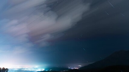 Wall Mural - city lights and stars trails over night sky in spain, time lapse