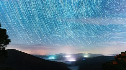 Wall Mural - night sky stars with trails above mountainous landscape, time lapse