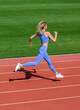 © Yevhen - Sport backgrounds. Girl runner ready for sports exercise. Athlete running on athletic track. Young sportswoman sprint on a running track outdoors on stadium.