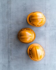 Aufkleber - Modern Construction Site Aesthetic Trio of Yellow Hard Hats on Concrete Surface - Symbolizing Diverse Teamwork and Safety in Contemporary Architecture and Urban Development