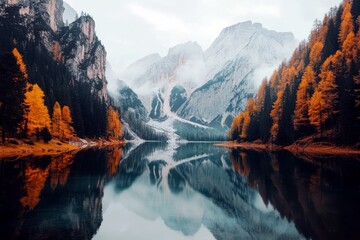  Majestic autumn landscape with vibrant orange trees and serene lake reflecting towering mountain peaks in misty atmosphere