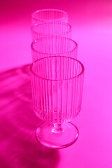 Sticker - Empty glasses on pink background, closeup. Color tone effect