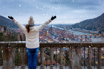 Wall Mural - A happy woman enjoys the panoramic view over the cityscape of Heidelberg, Germany, during winter time with snow