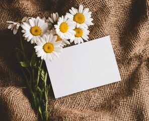 Wall Mural - Photo of a white blank card and a bouquet of daisies on a brown jute background, a mockup template for postcard design. 