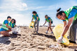 © charmedlightph - Group of eco volunteers picking up plastic trash on the beach - Activist people collecting garbage protecting the planet - Ocean pollution, environmental conservation and ecology concept.