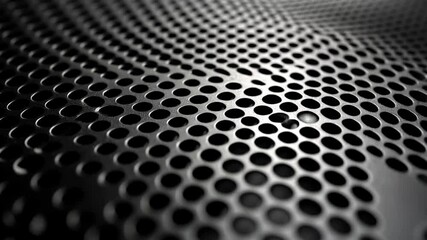 Close up of a black metal surface with many small holes. The surface is very dark and the holes are very small