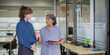 © Raushan_films - Indian senior old elder boss women lady standing hold book file make new project indoor office young adult expert intern girl older staff do work talk day task read report share ideas plan job place