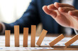 © sathon - Abstract representation of dominoes made of financial charts falling, stopped by a hand, symbolizing crisis management and risk strategy