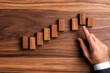 © sathon - Business meeting table with dominoes set up in a pattern, one hand stopping them mid-fall, symbolizing strategic planning and risk mitigation