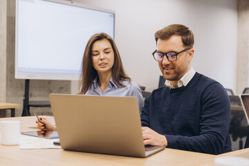 Wall Mural - Professional team working together, analyzing data on laptop in modern workplace environment