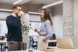 © anatoliycherkas - Colleagues drinking coffee and conversing near large windows, sharing ideas in contemporary workplace with natural light streaming inside