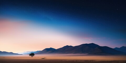 A lone tree stands in a vast, empty field. The sky is dark and starry, and the mountains in the distance are silhouetted against the horizon. Concept of solitude and peacefulness