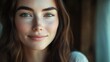 © The 2R Artificiality - Close-up of a beautiful brunette woman with natural skin and soft smile in warm soft lighting indoors, showcasing light neutral makeup and serene expression.