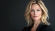 © The 2R Artificiality - Portrait of confident middle-aged businesswoman with wavy blonde hair against dark grey backdrop showcasing professional attire and natural beauty