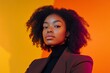 © Sergio - Confident young woman with natural hair poses against vibrant orange backdrop in modern studio setting