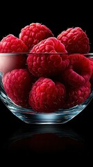 Wall Mural -   A bowl of raspberries sits on a black table, accompanied by a glass bowl filled with more