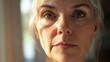 © The 2R Artificiality - Close-up portrait of a 50-year-old mature woman with silver hair and natural beauty, showcasing soft skin textures and subtle expressions indoors with warm lighting.