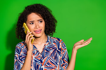 Poster - Photo of doubtful pretty lady wear print shirt talking modern device looking empty space isolated green color background