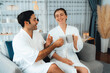 © InfiniteFlow - Beauty or body treatment spa salon vacation lifestyle concept with couple wearing bathrobe relaxing with drinks in luxurious hotel spa or resort room. Vacation and leisure relaxation. Quiescent