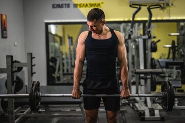 young muscular man hold weights barbell for exercise in a gym