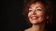 © The 2R Artificiality - portrait of a joyful middle-aged woman with curly hair smiling brightly in studio with black backdrop highlighting her luminous skin and expressive features