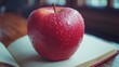 © izzuddin - Fresh red apple with water droplets resting on an open notebook in a cozy indoor setting