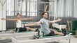 © InfiniteFlow - Two clients performing synchronized arm extensions on Pilates reformer machines. Happy pilates partner seated twist on the reformer for enhancing flexibility and building balance, control. Habituate.