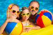 © Sunny studio - Happy family having fun in swimming pool on summer vacation