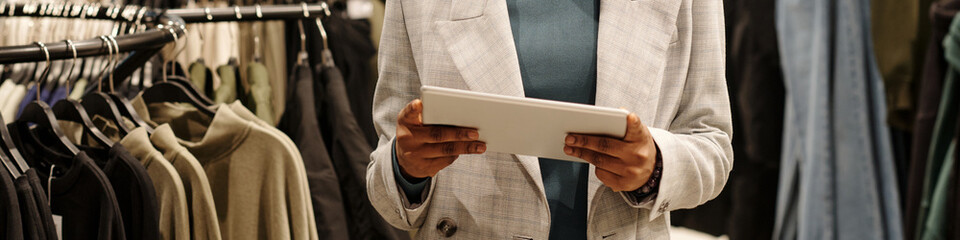 Aufkleber - Header of young elegant female shop assistant in white blazer using tablet while standing in front of camera in showroom