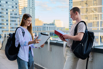 Wall Mural - Talking teenage college age students with textbooks notebooks, modern city background