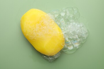 Canvas Print - Soap bar with foam on green background, top view