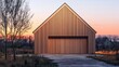 © Andrew - Modern Wooden Barn at Sunset: A striking modern barn clad in warm cedar wood, featuring a large garage door, stands silhouetted against the backdrop of a stunning sunset.