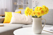© Pixel-Shot - Daffodil flowers in jug on coffee table in living room