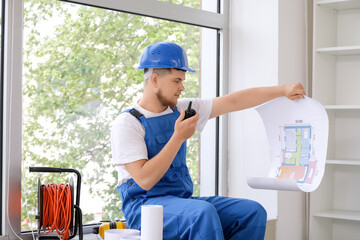 Wall Mural - male contractor with house plan talking on radio transmitter in room