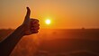 © Alfred - Hand thumbs up backlit by desert sunset