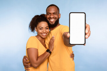 Wall Mural - new awesome mobile app. african american couple presenting smartphone with mockup, promoting applica