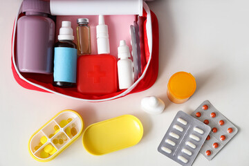 Poster - First aid kit with medicines on white table, top view