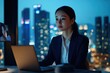 © Art - A businesswoman works late at night in a modern office, illuminated by city lights.