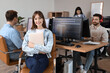 © Pixel-Shot - Female programmer with laptop and her team sitting in office